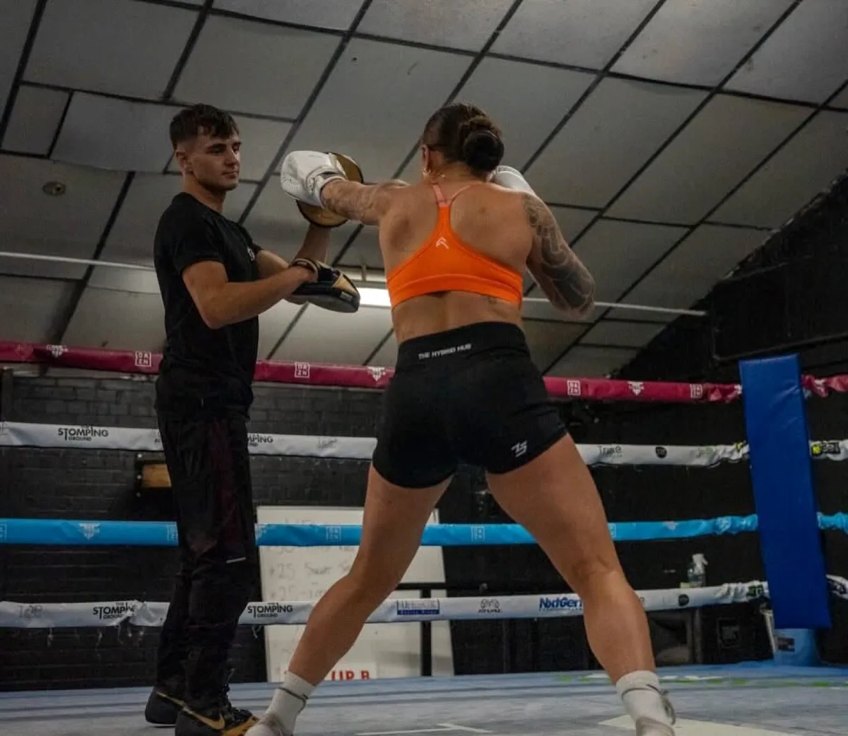 Coach Aiden Dann holding pads for a boxer in the ring at Intense Boxing Plymouth